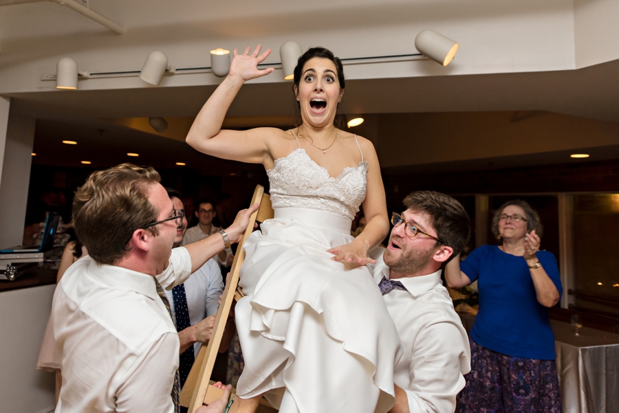 A bride being lifted in a chair during her wedding reception.